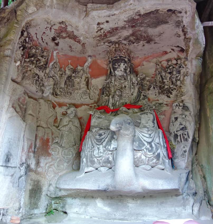 Large painted figure seated on a sculpted peacock at Peacock Cave