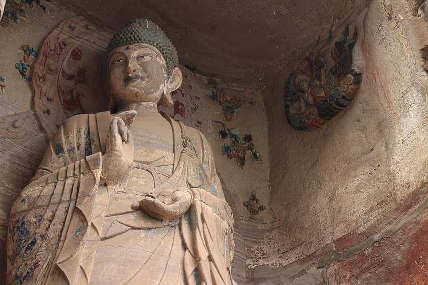 Low-angle close view of a monumental standing figure at Yuanjue Cave
